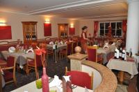 a woman standing in a restaurant with tables and chairs at Impuls Hotel Tirol in Bad Hofgastein