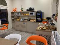 a kitchen with orange chairs and a counter with a microwave at Hotel Biney in Rodez