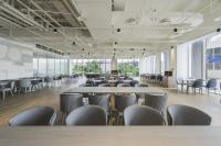 Una gran sala con mesas, sillas y ventanas. en Golden Tulip FAB Hotel New Taipei, en Tamsui