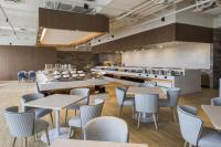 Un restaurante con mesas y sillas y una cocina. en Golden Tulip FAB Hotel New Taipei, en Tamsui