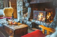 a living room with a fireplace and a table with wine glasses at Hôtel Le Sherpa Val Thorens in Val Thorens