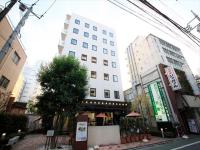 Un edificio alto y blanco en una calle de la ciudad. en Urban Hotel Tokyo Fuchu Nishiguchi, en Fuchu