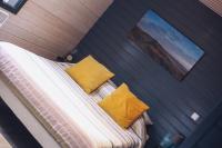 a bed with two yellow pillows in a room at Au Cap Norwoe in Saint-Quentin-en-Tourmont