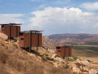 three buildings on top of a hill in the desert at Encuentro Guadalupe in Valle de Guadalupe