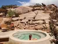 a woman is sitting in a hot tub in a mountain at Encuentro Guadalupe in Valle de Guadalupe