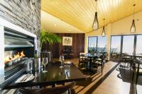 a dining room with tables and a fireplace at Castaways Resort in Waiuku
