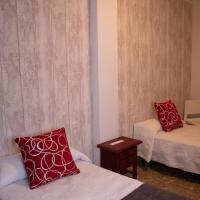 a room with two beds with red pillows and a table at Hostal Caminito del Rey in Alora
