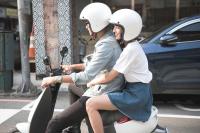 two women wearing helmets riding a scooter on the street at P&amp;F Hotel in Taichung
