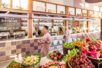 Una persona parada en una panadería con frutas y verduras. en Fusion Resort Cam Ranh - All Spa Inclusive, en Cam Ranh