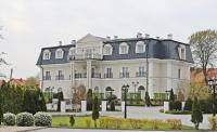 a large white house with a black roof at Hotel Toscania in Włoszakowice