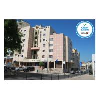 Un gran edificio blanco con coches aparcados en un estacionamiento. en Hotel Arangues, en Setúbal