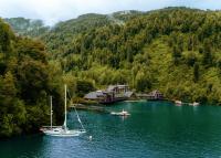 a sailboat is docked at a dock in a lake at Puyuhuapi Lodge &amp; Spa in Puerto Puyuhuapi