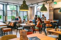people sitting in a restaurant with tables and chairs at Hotel & Eetk'fee de VLiK in Ospel