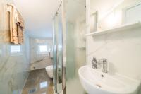 a white bathroom with a sink and a toilet at Rooms &amp; Apartments Barišić in Mlini