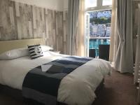 a bedroom with a bed with a large window at Shellseekers Guest House in Looe