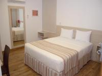 Un dormitorio con una cama grande con sábanas blancas. en Hotel Rede 1, en Campos dos Goytacazes