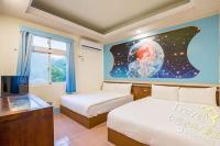 a room with two beds and a tv and a mural at Blue Sea Romance B&amp;B in Green Island