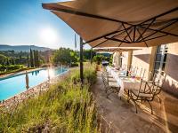 een tafel en stoelen onder een parasol naast een zwembad bij Countryhouse Villa Rey in Panicale