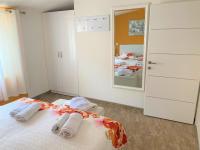 a white bedroom with a bed and a mirror at Apartment Beach in Makarska
