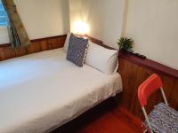 a small bedroom with a white bed and a red chair at Kao Mama B&amp;B in Jiufen