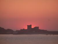 a sunset over the water with a castle in the background at Hotel Bel Air in Saint-Jean-de-Luz