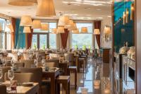 Un restaurante con mesas y sillas y grandes ventanales. en Vila Galé Collection Serra da Estrela, en Manteigas