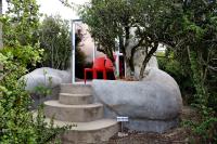 a red chair and a tree in a garden at Addo Dung Beetle Guest Farm in Addo