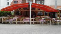 a restaurant with tables and chairs under a red umbrella at Südtiroler Stubn Café und Restaurant in Arnstadt
