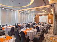 a conference room with tables and chairs and a screen at HARRIS Hotel Batam Center in Batam Center