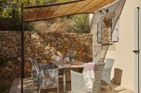 a table and chairs on a patio with a stone wall at Château Les Carrasses in Capestang