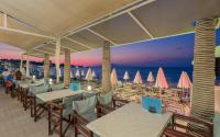 um restaurante na praia com mesas e cadeiras em Phoenix Beach Hotel em Plános