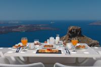 a table with food and drinks and a view of the ocean at Tholos Resort in Imerovigli