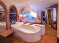 a bathroom with a bath tub with a painting on the wall at Bavaria Lifestyle Hotel in Altötting