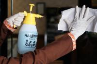 a person wearing gloves holding a bottle of bleach at Silom Space Hostel in Bangkok
