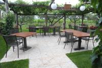 eine Terrasse mit Tischen und Stühlen unter einer Pergola in der Unterkunft Agriturismo Sol De Montalto in Rivoli Veronese