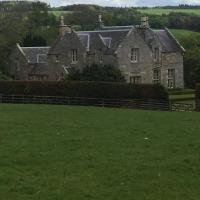 an old stone house with a fence in a field at Hundalee House in Jedburgh