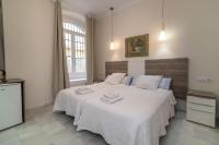 a bedroom with two beds with white sheets and a window at Casa Patio del Panadero in Cádiz