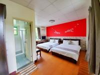 a bedroom with two beds and a red wall at Pulicity Villa B&amp;B in Puli
