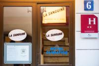 a door with signs on the front of a hotel entrance at Hôtel La Sanguine in Paris