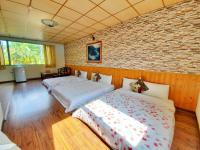 two beds in a room with a brick wall at Pulicity Villa B&amp;B in Puli