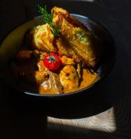 Un plato de comida con carne y un tomate. en Hagen`s Hotel "eat & meet" Restaurant Bar Lounge, en Haren