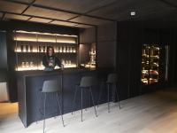 Una mujer parada en un bar en una habitación con taburetes. en Casa Grande Hotel, en Grañón