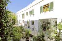 a white building with green shuttered windows and plants at Apartamentos Gravina in Tarifa