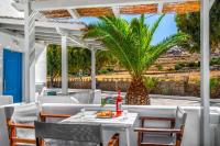 a table and chairs on a patio with a palm tree at Coralli Seaside Resort in Livadakia