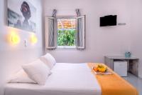 a white bedroom with a large bed with a table at Coralli Seaside Resort in Livadakia