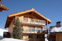 a large wooden building with a balcony in the snow at Grandes Rousses Hotel &amp; Spa in L&#39;Alpe-d&#39;Huez