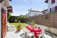 einen roten Tisch mit weißen Stühlen auf einer Terrasse in der Unterkunft Charming Basque villa with garden - Bayonne - Welkeys in Bayonne