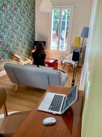 a woman sitting on a couch in a living room with a laptop at La Maisonnette in Vichy