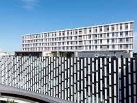 un edificio blanco alto con una valla delante en Kawagoe Tobu Hotel, en Kawagoe
