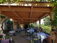 a patio with tables and chairs under a wooden pergola at Le Mas du Lingousto in Cuers